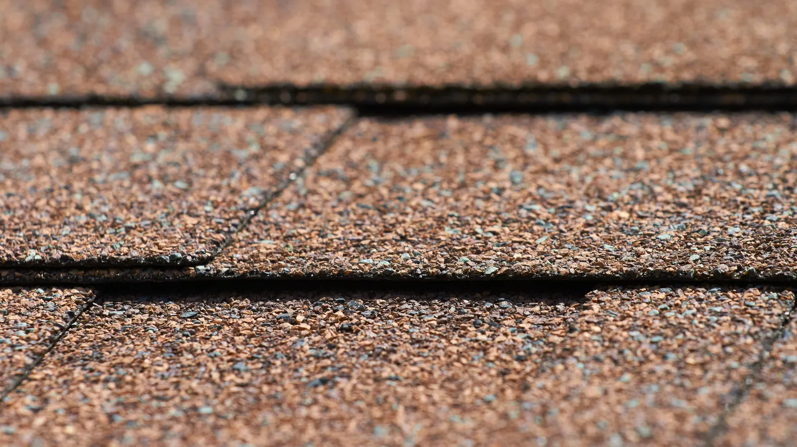 Macro view showing overlapping tab edges and brown asphalt shingle granules